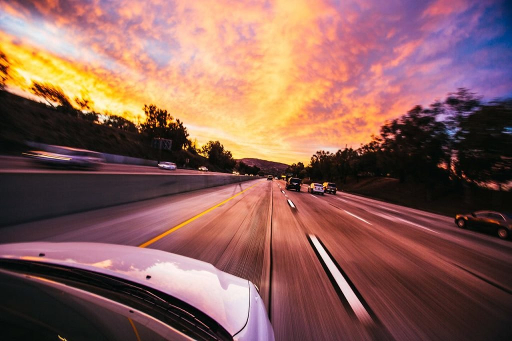 Motion blur of cars speeding on an Irvine highway at sunset with vibrant skies.